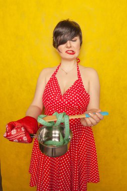 plump girl in a red polka-dot dress stands with an empty pan and a centimeter tape on a spoon, wants to eat, but diets for health and figure clipart