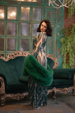 bir lüks uzun pullu dantel şık beyaz kız retro vintage lüks mobilya oda poz onun elinde bir yeşil tüylü boa ile elbise