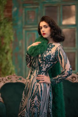 bir lüks uzun pullu dantel şık beyaz kız retro vintage lüks mobilya oda poz onun elinde bir yeşil tüylü boa ile elbise