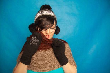 güzel esmer kız moda siyah örme kış şapka ve sıcak güzel mittens mavi stüdyo sağlam zemin üzerine giyiyor