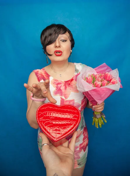 Bahar elbise sevimli gülümseyen kız stüdyoda mavi bir arka plan üzerinde tulip buket pembe taze tutar. o gerçekten hediye ve kesinlikle mutlu bulunuyor.