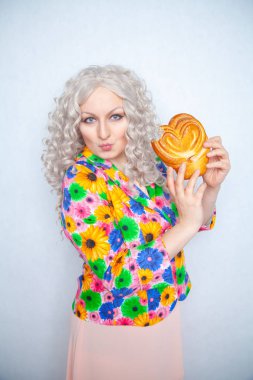 sevimli tombul kız yaz ceket çiçekli beyaz kıvırcık saçlı tatlı pasta çörek bir kalp şeklinde tutar.