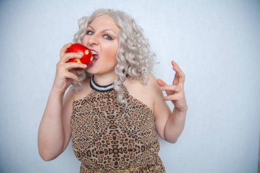 Yazlık elbise giyen ve beyaz arka planda yalnız büyük kırmızı elma ile poz tombul sarışın kız 