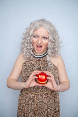 Yazlık elbise giyen ve beyaz arka planda yalnız büyük kırmızı elma ile poz tombul sarışın kız 