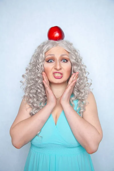 cute girl with a big red Apple on her head on a white solid Studio background
