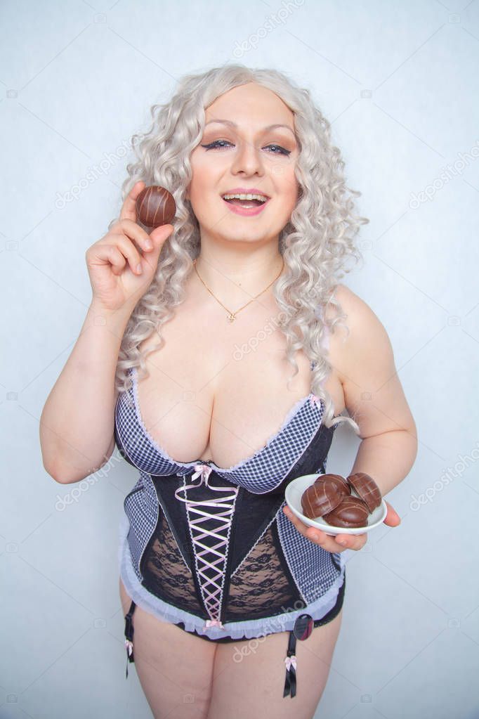 charming plump blonde girl with a plate of chocolate cakes on a white Studio background alone