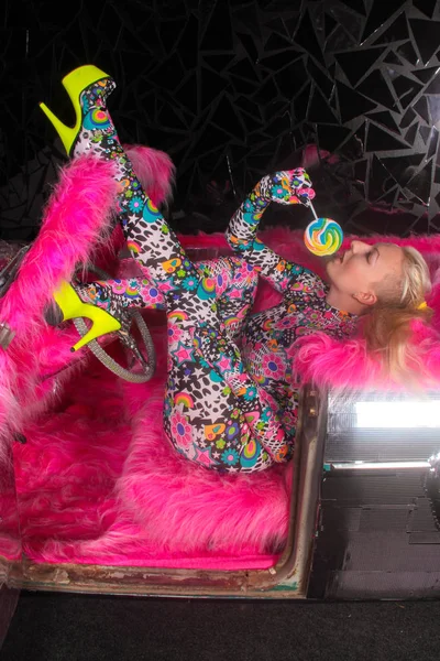 club party blonde girl in acid anime style spandex catsuit with mirror car with pink fur ready for crazy clubbing life