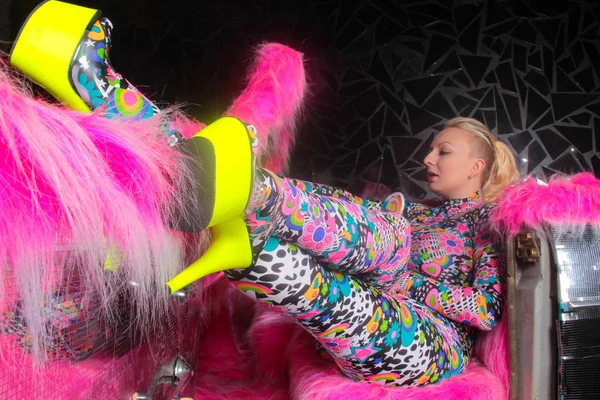 club party blonde girl in acid anime style spandex catsuit with mirror car with pink fur ready for crazy clubbing life