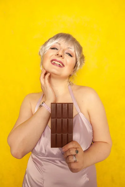 Menina Muito Gordinha Com Barra Chocolate Estúdio Amarelo Fundo Sólido — Fotografia de Stock