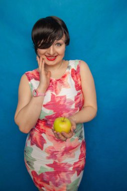 Yeşil elma stüdyo düz arka plan blus üzerinde tutan tombul artı boyutu kadın