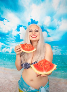 sevimli tombul sarışın bir mayo büyük göğüsler ile karpuz bir parça ile standları ve yemek ve dinlenme sahiptir