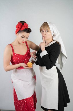 iki sevimli kız arkadaşım için bir kostüm cosplay parti giyinmiş. bir kız pinup tarzı bir ev hanımı olarak giyinmiş, ikinci kadın bir rahibe olarak bir şırınga ile giyinmiş. Beyaz bir arka plan üzerinde duruyorlar.