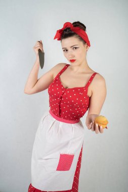 Kız ev kadını kırmızı vintage puantiyeli elbise kadar tehlikeli PIN onun elinde büyük bir bıçak ile duruyor ve öfkeyle beyaz katı studio özgeçmişlerine sevinir