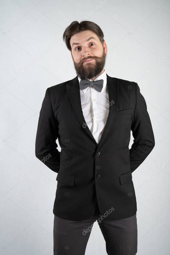 caucasian servant with a beard in a formal business suit stands with a steel tray in his hand and a glass of wine on a white solid background in the Studio