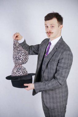 iş takım elbiseli genç adam şapkasını leopar sütyen çeker ama hileler merak ve servet ile istedi. duygusal erkek beyaz stüdyo düz arka plan üzerinde aldattım hissediyorum.