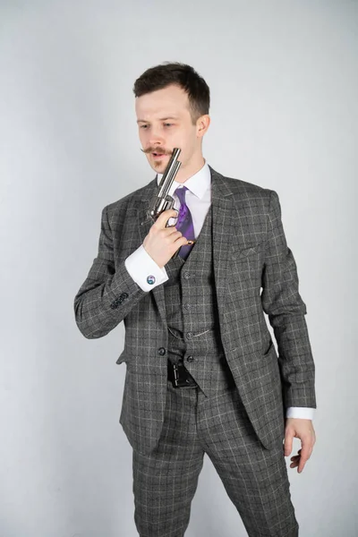 vintage English detective with a checkered business suit with a gun on a white studio solid background
