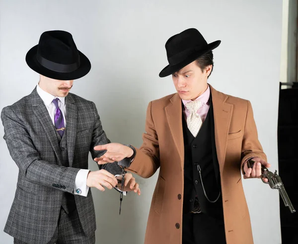 two friends dressed in vintage clothes and depict retro detectives and spies in English classic style on a white studio background