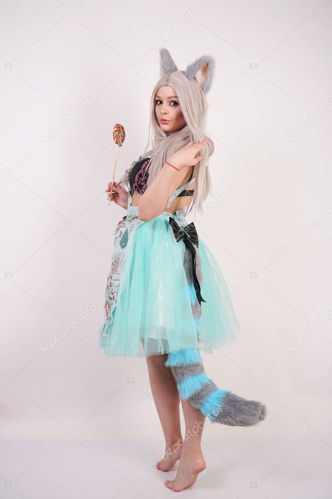 charming caucasian kitty teenage girl in kitchen apron with colorful Lollipop on white Studio background