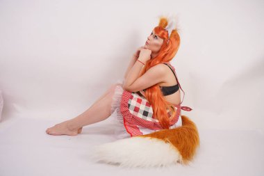 Tüylü büyük kulakları ile turuncu uzun peruk ve uzun kabarık kuyruk kırmızı mutfak ekose apron giyen beyaz bir arka planda yalnız yalınayak poz büyüleyici Fox kız