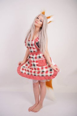 sevimli genç beyaz kız mutfak ekose önlük kabarık Fox kulaklar ve uzun kürk kırmızı kuyruklu Studio beyaz arka plan üzerinde çıplak ayakla ayakta