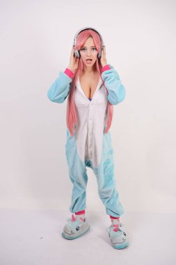 Mavi tek boynuzlu at pijama ve yumuşak komik terlik Studio beyaz arka plan üzerinde pembe uzun saçlı sevimli genç kız