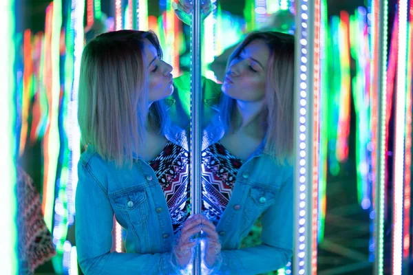 甜美的高加索女孩走在一个镜子迷宫与五颜六色的二极管 并享受一个不寻常的吸引力的房间在城市 — 图库照片