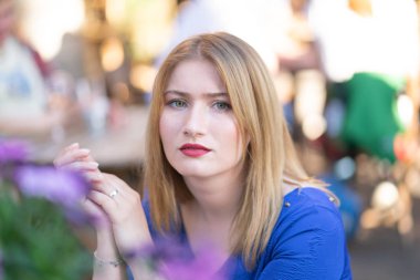 Büyüleyici bir şehir kafe yalnız ve bekleyen yalnız yaz bir masada oturan mavi elbiseli Beyaz sarışın kız