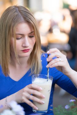 bir şehir kafede yalnız ve bekleyen bir masada oturan bir mavi elbiseli çekici beyaz sarışın kız