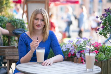 bir şehir kafede yalnız ve bekleyen bir masada oturan bir mavi elbiseli çekici beyaz sarışın kız