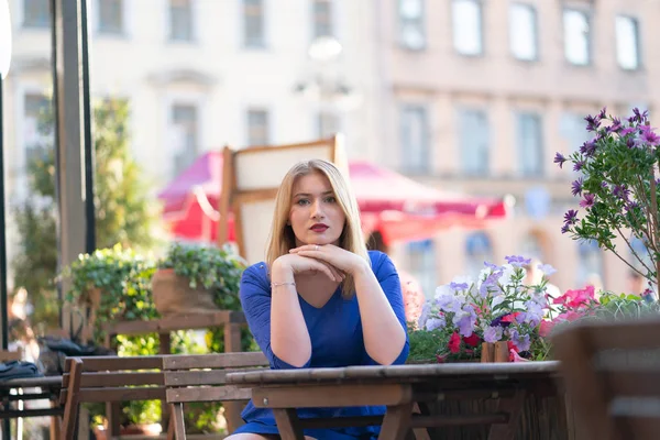 Charmig Kaukasiska Blond Flicka Blå Klänning Som Sitter Vid Ett — Stockfoto