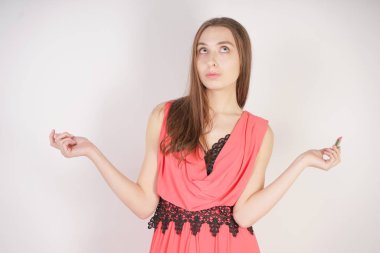 bir Abiye içinde büyüleyici bir genç beyaz kız makyaj olmadan standları ve stüdyo beyaz bir arka planda açık pembe ruj tutar