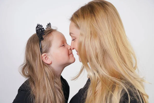 cute kind caucasian blonde mom and daughter posing on white background. a parent and a child experience love and hug.