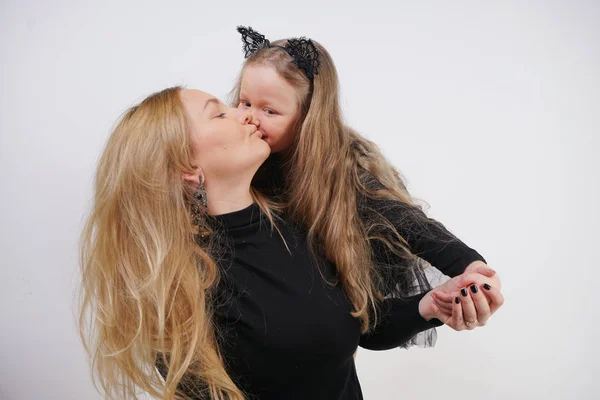 cute kind caucasian blonde mom and daughter posing on white background. a parent and a child experience love and hug.