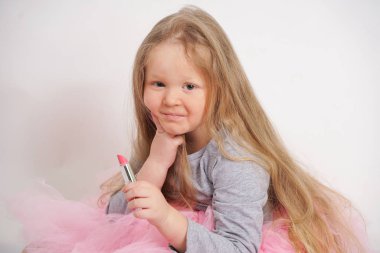 biraz beyaz sarışın kız oturur ve annesinin pembe ruj ile makyaj yapmak ve er bir yetişkin olmak istiyor