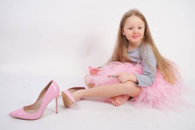 küçük bir kız oturur ve annesinin yüksek topuk ayakkabıları koyar, ruj ile dudakları boyar ve erken bir yetişkin olmak istiyor