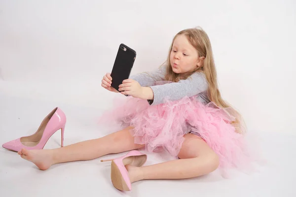 어린이 소녀가 앉아서 어머니의 분홍색 신발을 스튜디오 배경에 그녀의 스마트 — 스톡 사진
