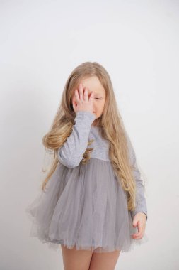 Stüdyo beyaz arka planda facepalm sembolü ile yüzünde bir el ile küçük kız çocuk ayakta