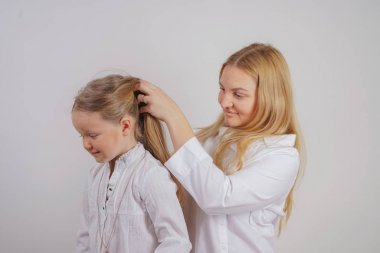 Anne ve kızı beyaz gömlek uzun sarışın saç stüdyo katı bir arka planda poz ile. büyüleyici bir aile birbirleriyle ilgilenir ve örgü yapar.