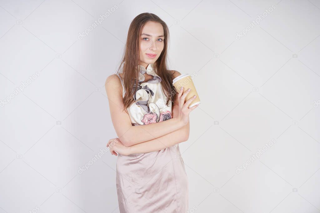 cute teenager caucasian girl in fashionable evening dress with paper coffee Cup on white background in Studio alone