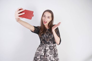 sevimli Kafkas dostu kız elinde bir cep telefonu ile standları ve tek başına stüdyo beyaz bir arka planda mutlu bir duygusal selfie alır