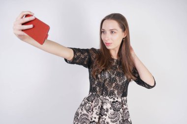 sevimli Kafkas dostu kız elinde bir cep telefonu ile standları ve tek başına stüdyo beyaz bir arka planda mutlu bir duygusal selfie alır