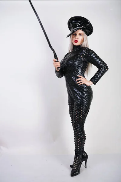 cruel fashionable bdsm lady with curves dressed in black catsuit with sexy holes and posing on a white background in the Studio