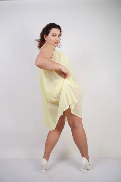 pretty chubby girl wearing fashionable yellow underwear and loves her body and herself. plump woman in lingerie on white background.