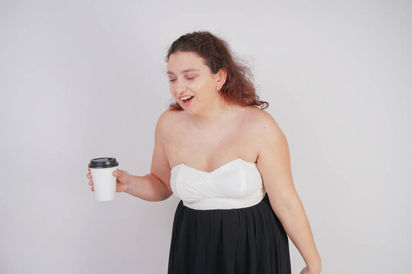 emotional plus size woman with paper cup of tea in her hands on white background