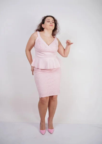 白いスタジオの背景にピンクのファッショナブルなドレスで踊るかなりぽっちゃりポジティブな女の子 — ストック写真