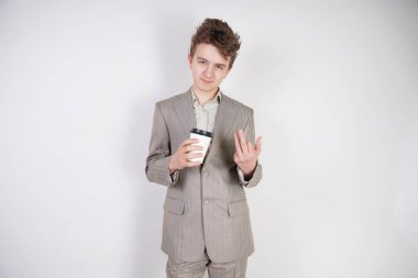 beyaz stüdyo arka plan üzerinde elinde kahve kağıt Fincan ile gri iş elbisesi genç erkek