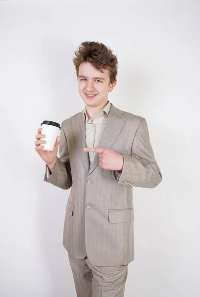 青少年男性在灰色西装与纸杯咖啡在白色工作室背景 — 图库照片