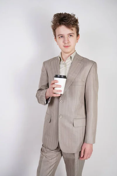 青少年男性在灰色西装与纸杯咖啡在白色工作室背景 — 图库照片