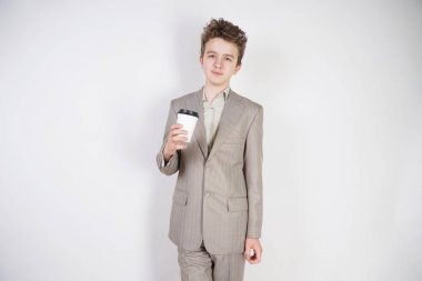 beyaz stüdyo arka plan üzerinde elinde kahve kağıt Fincan ile gri iş elbisesi genç erkek