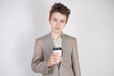 beyaz stüdyo arka plan üzerinde elinde kahve kağıt Fincan ile gri iş elbisesi genç erkek